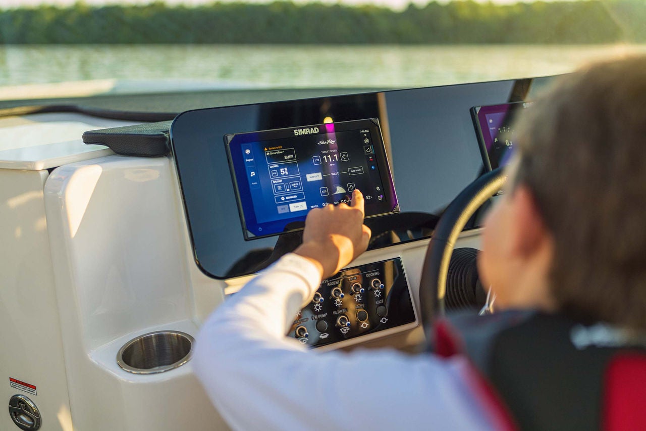 Kid using a touchscreen display at the helm of an SDX 230 Surf