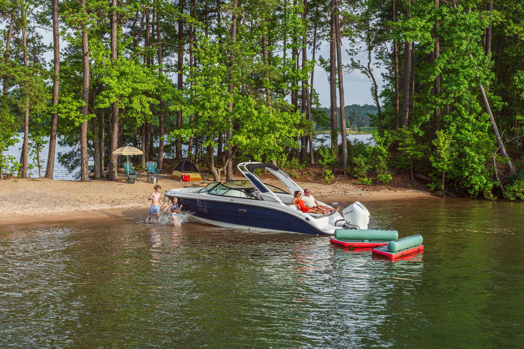 Kids swimming next to an SDX 250 Outboard by a campsite