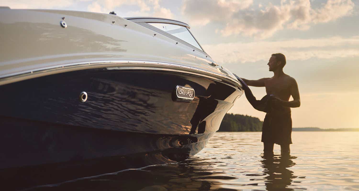 Man standing next to Black Sea Ray SPX 190 at sunset
