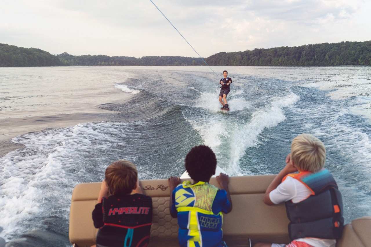 Three Kids on Back of Sea Ray Boat Watching Wakeboarder