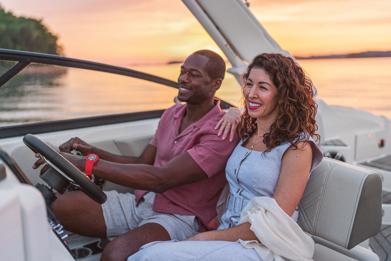 Couple at the helm of an SDX 270 Outboard at sunset